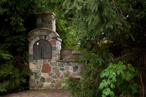 a stone wall with a door on it with trees at Dadajowa Osada - Dadaj in Biskupiec