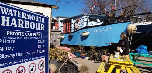 a woman standing next to a sign next to a boat at The Poplars Guest House in Combe Martin