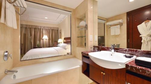 uma casa de banho com um lavatório e um espelho grande em Hotel Equatorial Shanghai em Xangai
