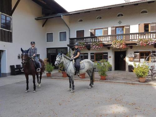 Dos personas montando a caballo delante de un edificio en Am Valtlhof, en Grabenstätt