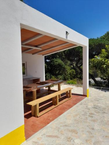 an outdoor patio with a wooden table and a bench at Nadadouro Eco-country-cottage in Nadadouro