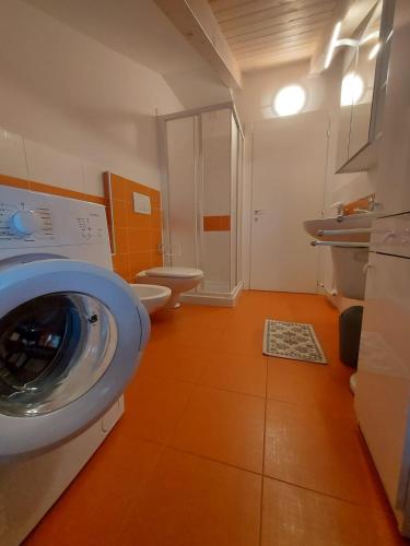 a bathroom with a washing machine and two toilets at Appartamento Al Borgo in Cles