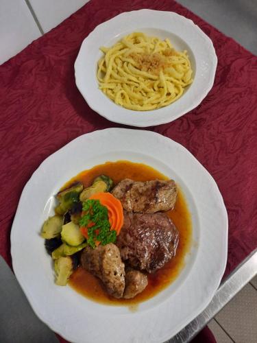 two plates of food with meat and noodles on a table at Cross-Country-Hotel Hirsch in Sinsheim