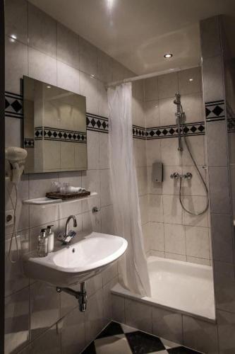 a bathroom with a sink and a shower and a tub at Hotel De Limbourg in Sittard