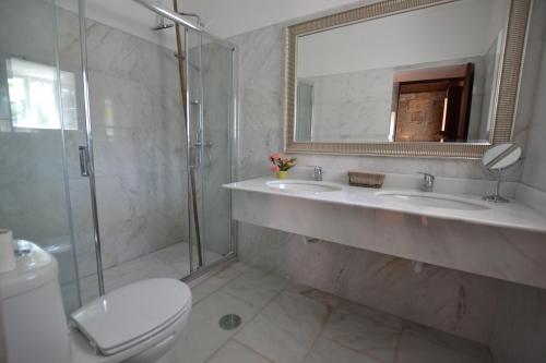 uma casa de banho com 2 lavatórios, um chuveiro e um WC. em Casa do Ribeiro em Guimarães