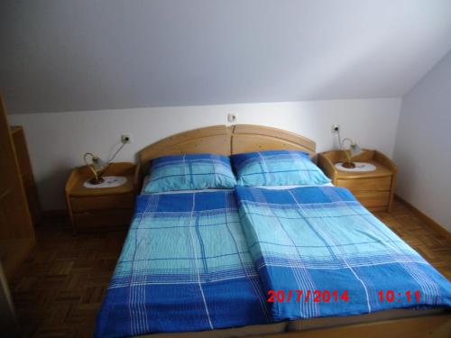 a bed with blue sheets on it with two night stands at Holiday Home Pri Srni in Bohinj
