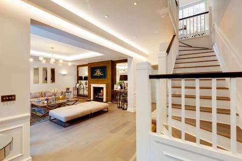 una sala de estar con una escalera que conduce a una sala de estar. en Flawless Eight-bedroom Cheyne Family home in the heart of Chelsea en Londres