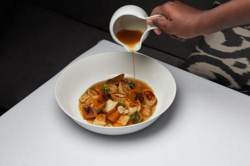 a person is pouring a cup of soup into a bowl at The Franklin London - Starhotels Collezione in London