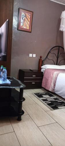 a bedroom with a bed and a table and a television at Sunview Lodge & Restaurant in Libwezi