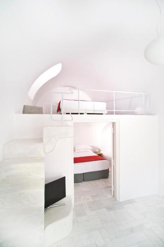 a white bedroom with a bed and a desk at Avista Suites in Imerovigli