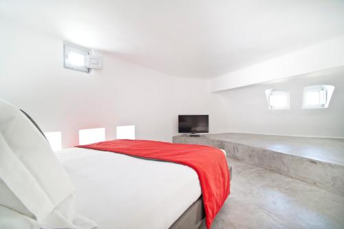 a white bedroom with a red blanket on a bed at Avista Suites in Imerovigli