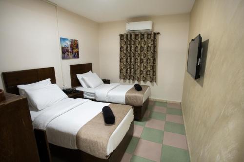 アカバにあるDarak hotelのベッド2台とテレビが備わるホテルルームです。