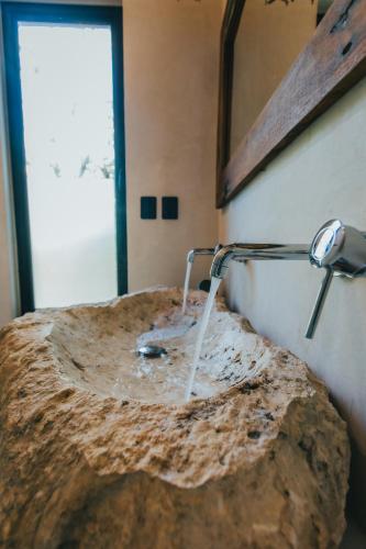 a bathroom with a rock sink and a mirror at Ambre & Epices Jungle Hotel & Spa in Tulum