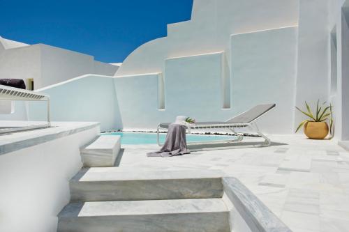 a woman sitting on a bench next to a pool at Avista Suites in Imerovigli