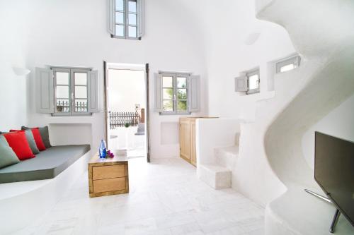 a white living room with a couch and a tv at Avista Suites in Imerovigli