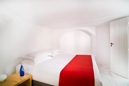 a bedroom with a white bed with a red blanket at Avista Suites in Imerovigli