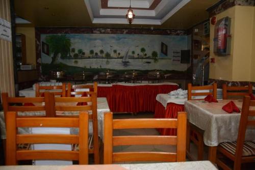a restaurant with tables and chairs and a painting on the wall at New Saint Catherine Hotel in Luxor