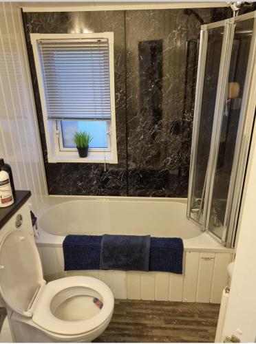 a bathroom with a toilet and a tub with a window at The Meridan Lodge - Close to beach - Swimming Pool & Amusements in Clacton-on-Sea