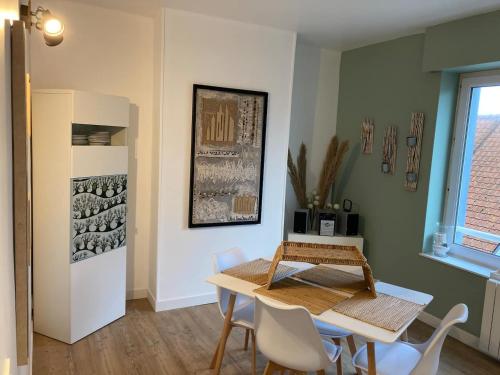 une salle à manger avec une table et des chaises blanches dans l'établissement Appartement cosy en duplex à 50m de la plage, à Le Portel
