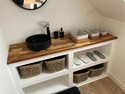 a bathroom with a sink and baskets on a shelf at Appartement cosy en duplex à 50m de la plage in Le Portel