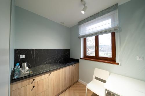 a kitchen with a counter top and a window at Pensjonat Dominikański in Krasnobród