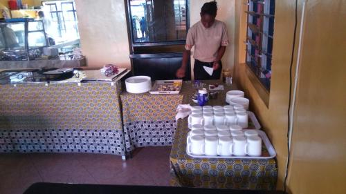 a man standing in a kitchen with a bunch of water bottles at Sunview Lodge & Restaurant in Libwezi