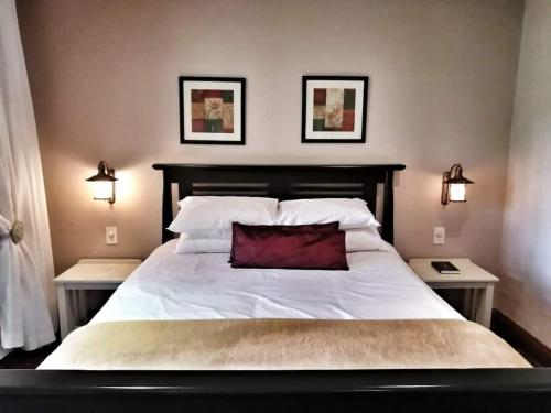 a bedroom with a large white bed with a red pillow at Trout River Falls in Lydenburg