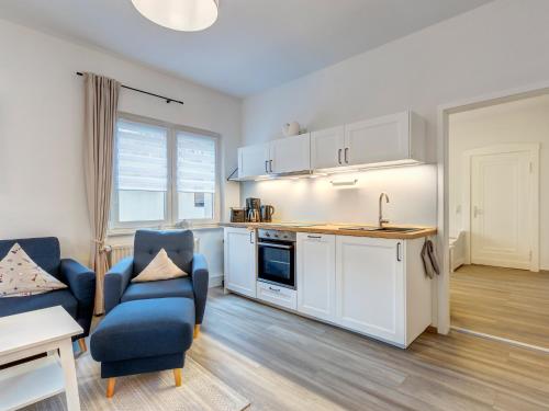une cuisine avec des placards blancs et une chaise bleue dans l'établissement Haus Barnheide - Wohnung Sandburg, à Bansin