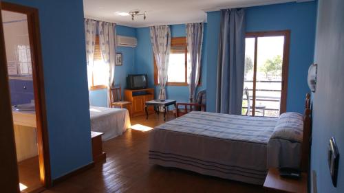 a bedroom with blue walls and a bed and a television at LAS GLORIAS in Torre de Santa María