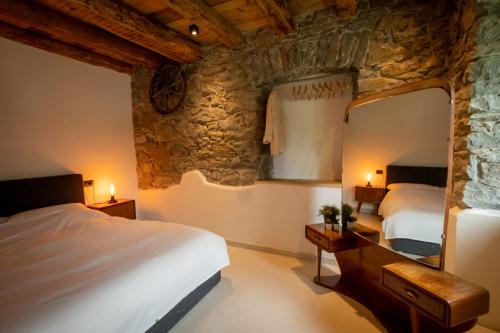 a bedroom with two beds and a stone wall at Appartamenti La Rocia in Rocca Pietore