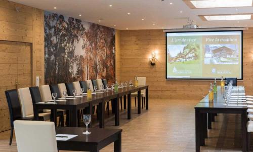 a conference room with tables and chairs and a screen at Waldhotel Doldenhorn in Kandersteg