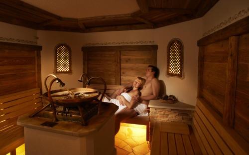 a man and woman sitting in a sauna with a baby at Waldhotel Doldenhorn in Kandersteg