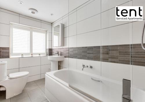 a bathroom with a tub and a toilet and a sink at COZY 2 BED Apt Steps to town centre by Tent Serviced Apartments Egham with Free Parking and Wifi in Egham
