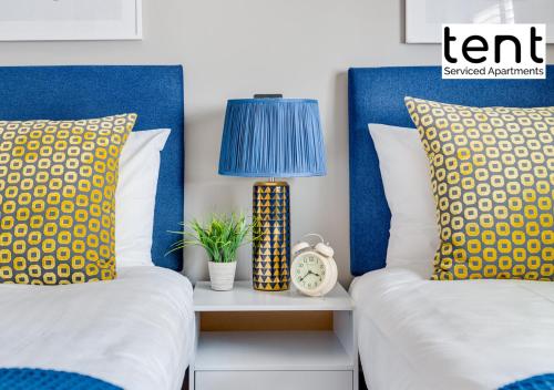 two beds with pillows and a lamp on a night stand at COZY 2 BED Apt, town centre, pkg, perfect for long stays in Egham