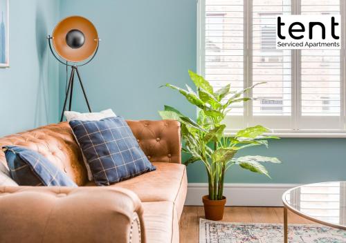 a living room with a brown couch and a plant at COZY 2 BED Apt, town centre, pkg, perfect for long stays in Egham