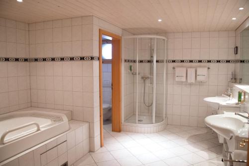 a bathroom with a tub and a shower and a sink at Waldhotel Doldenhorn in Kandersteg