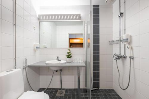 uma casa de banho com um lavatório e um chuveiro com um espelho. em Hotel Tuulonen em Tuulos