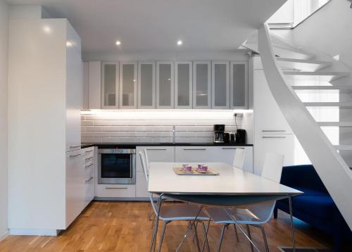 a kitchen with white cabinets and a table with chairs at townhouse on Arlanda Stockholm metro line - easy checkin in Sollentuna