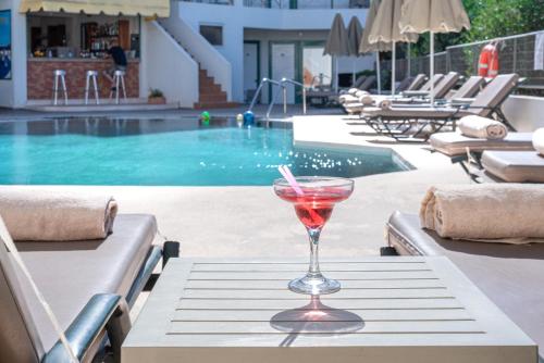 einen Drink in einem Glas auf einem Tisch in der Nähe eines Pools in der Unterkunft Bella Vista Hotel "by Checkin" in Hersonissos