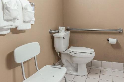 a bathroom with a toilet and a chair and towels at FairBridge Inn & Suites Poconos in Stroudsburg