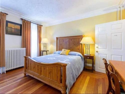a bedroom with a wooden bed with blue sheets and a table at Sunny Home B&B in Charlottetown