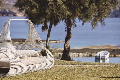 a wicker chair sitting on the grass by the water at Noon Beyond Accommodation in Pollonia