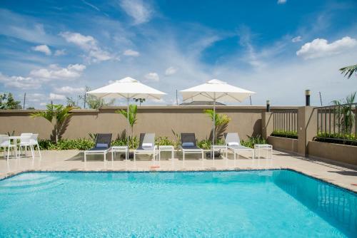 a swimming pool with white chairs and umbrellas at Lalibela Boutique Hotel in Lilongwe