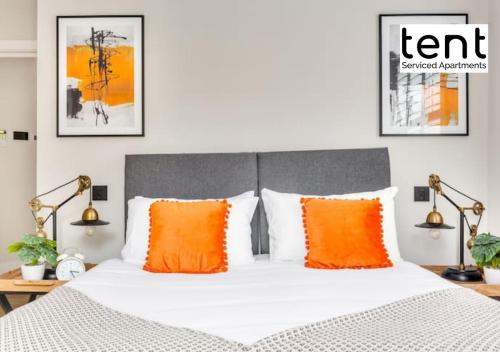1 dormitorio con 1 cama con almohadas de color naranja en Stunning City Centre Two Bedroom Apartment With Free Parking at Tent Serviced Apartments Staines, en Staines