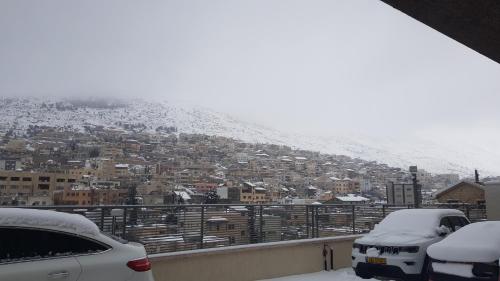 two cars parked on a balcony in the snow at Snow View Suite סוויטת סנו וויו in Majdal Shams