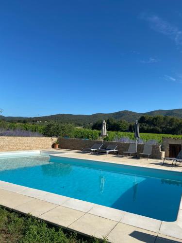 a swimming pool with chairs and a view of the mountains at Maison d'hôtes Bastide St Victor à 2,5 kilomètres de Lourmarin in Puyvert