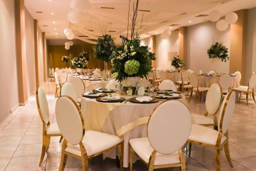 um salão de banquetes com uma longa mesa com cadeiras brancas em Hotel Puerta del Sol em David