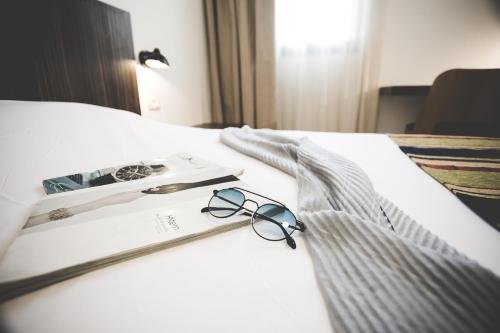 a pair of glasses and a book on a bed at Nof Tavor Hotel in Mizra‘