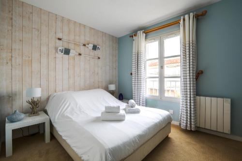 1 dormitorio con cama blanca y ventana en Sur l'ilot, au centre du port, vue UNIQUE !, en Saint-Martin-de-Ré