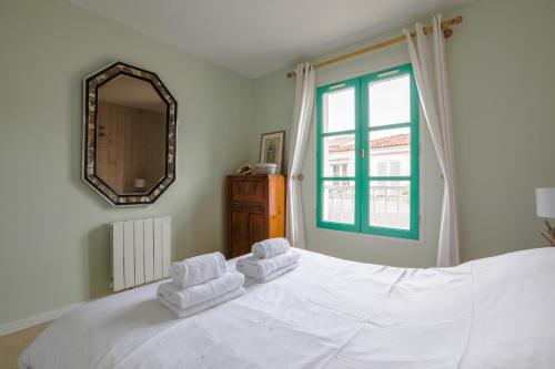 a bedroom with a white bed with two towels on it at Au coeur du port, vue unique, appartement pour 6 in Saint-Martin-de-Ré
